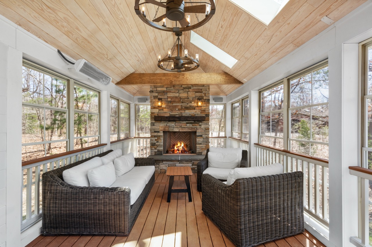 porch enclosure with a stone fireplace and furniture